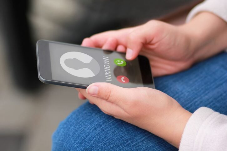 hands holding phone about to accept call from unknown number