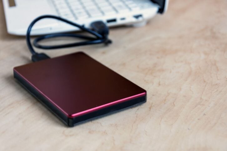 external hard drive and laptop keyboard on wooden table background