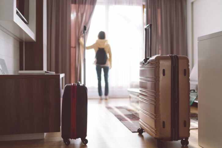 tourist woman opening blinds in hotel room