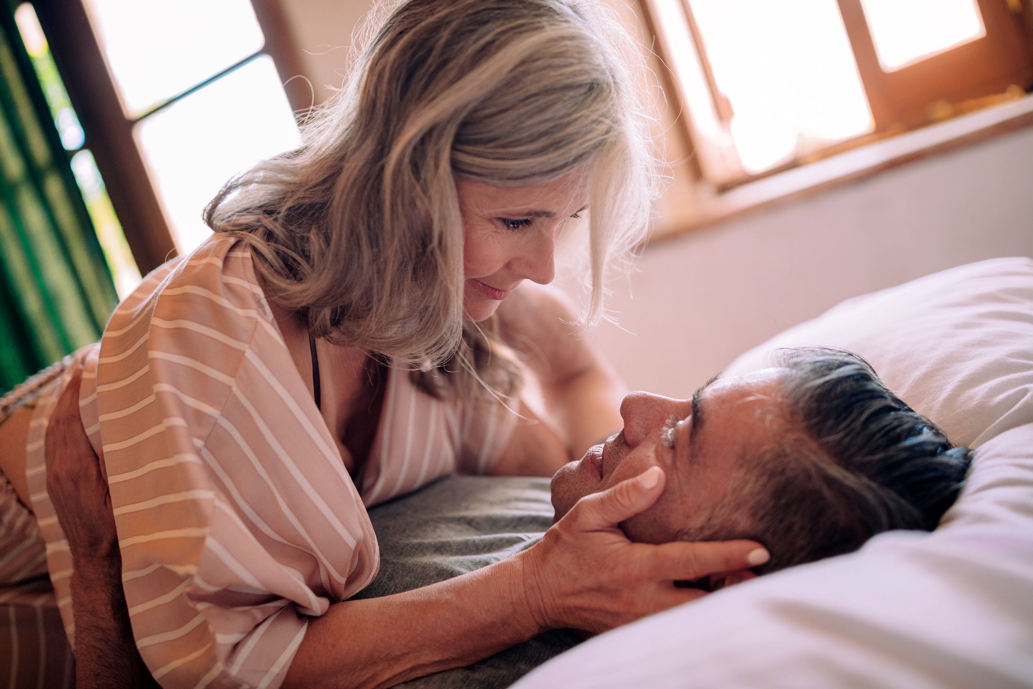 senior couple in bed looking at each other longingly