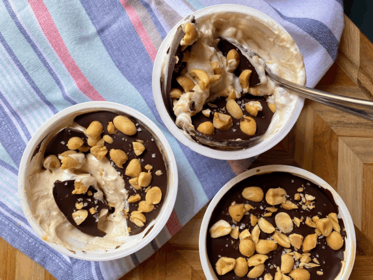 Three cups of yogurt covered in chocolate and peanuts