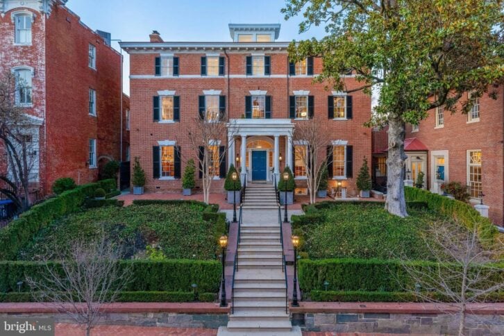red brick mansion with white trim and landscaped yard