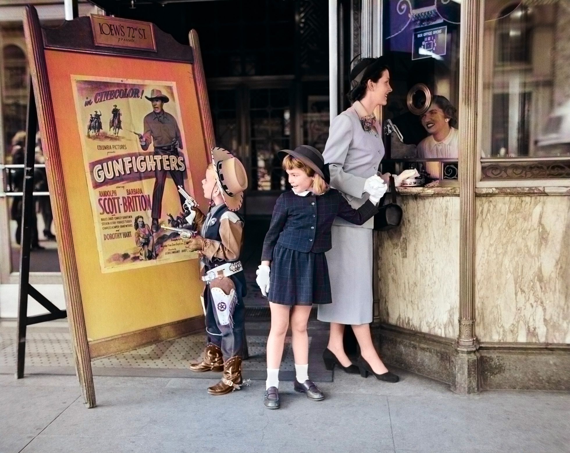 A woman and two children stand outside a movie theater box office. One child is dressed as a cowboy, looking at a "Gunfighters" poster, while the woman buys tickets and another girl stands beside her.