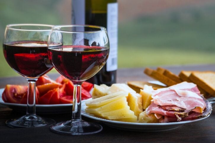 picnic with wine, cheese, toast, charcuterie, tomatoes, sunset in background