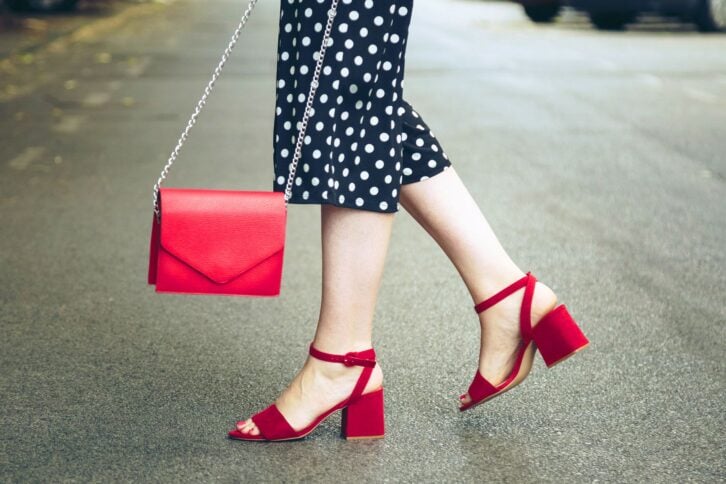 woman with purse and polka dot pants, red sandals crossing the street
