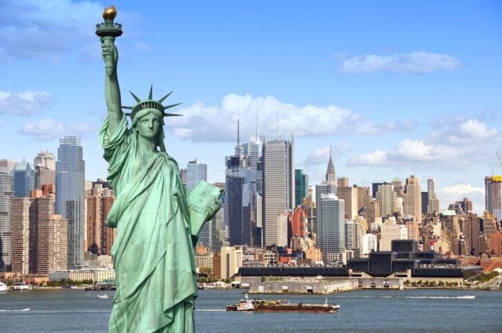 Statue of Liberty looking over Hudson River with New York City skyline.