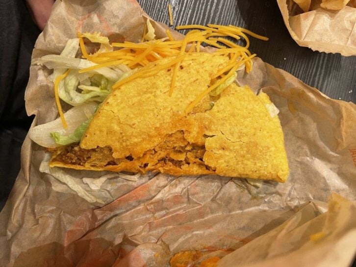 A smashed hard shell taco from Taco Bell with beef, cheese, and lettuce.