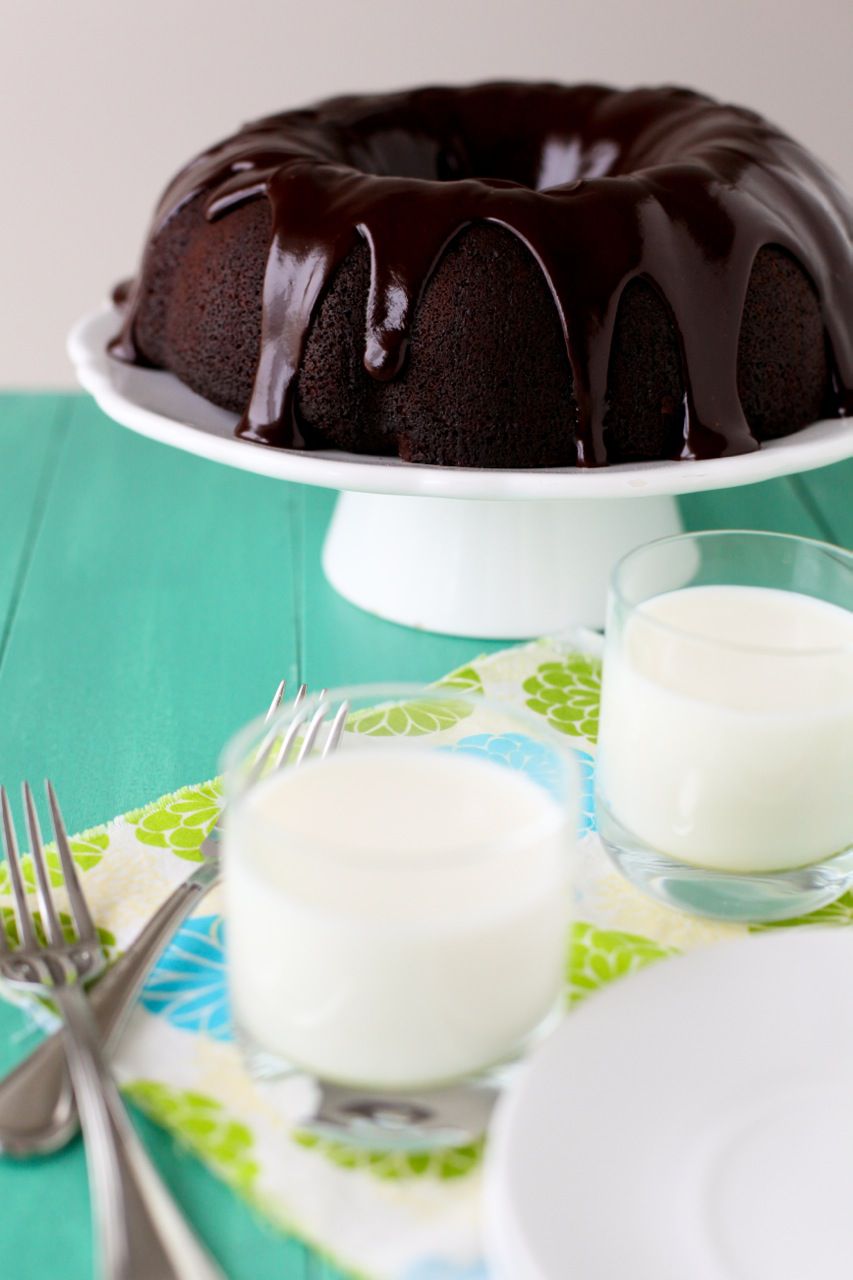 a chocolate tunnel of fudge cake on a pedestal with milk in front of it