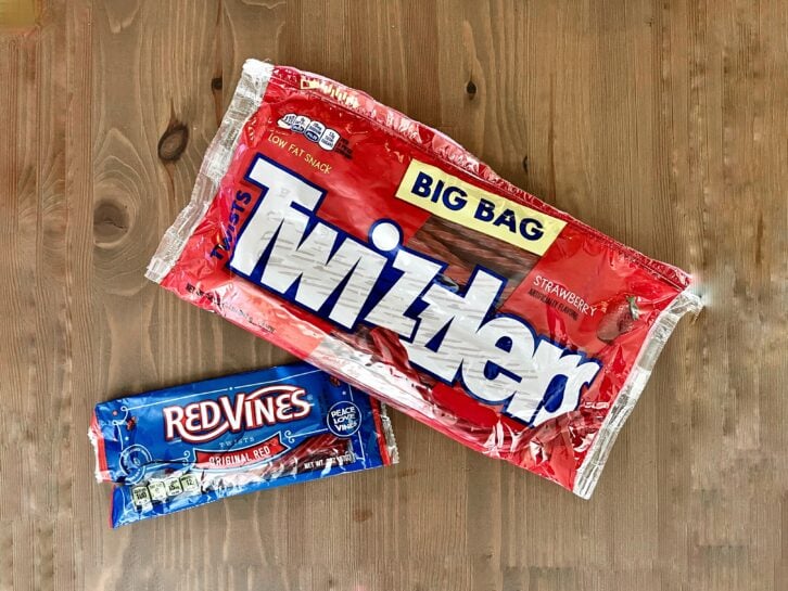 a bag of red vines next to a bag of twizzlers licorice candy