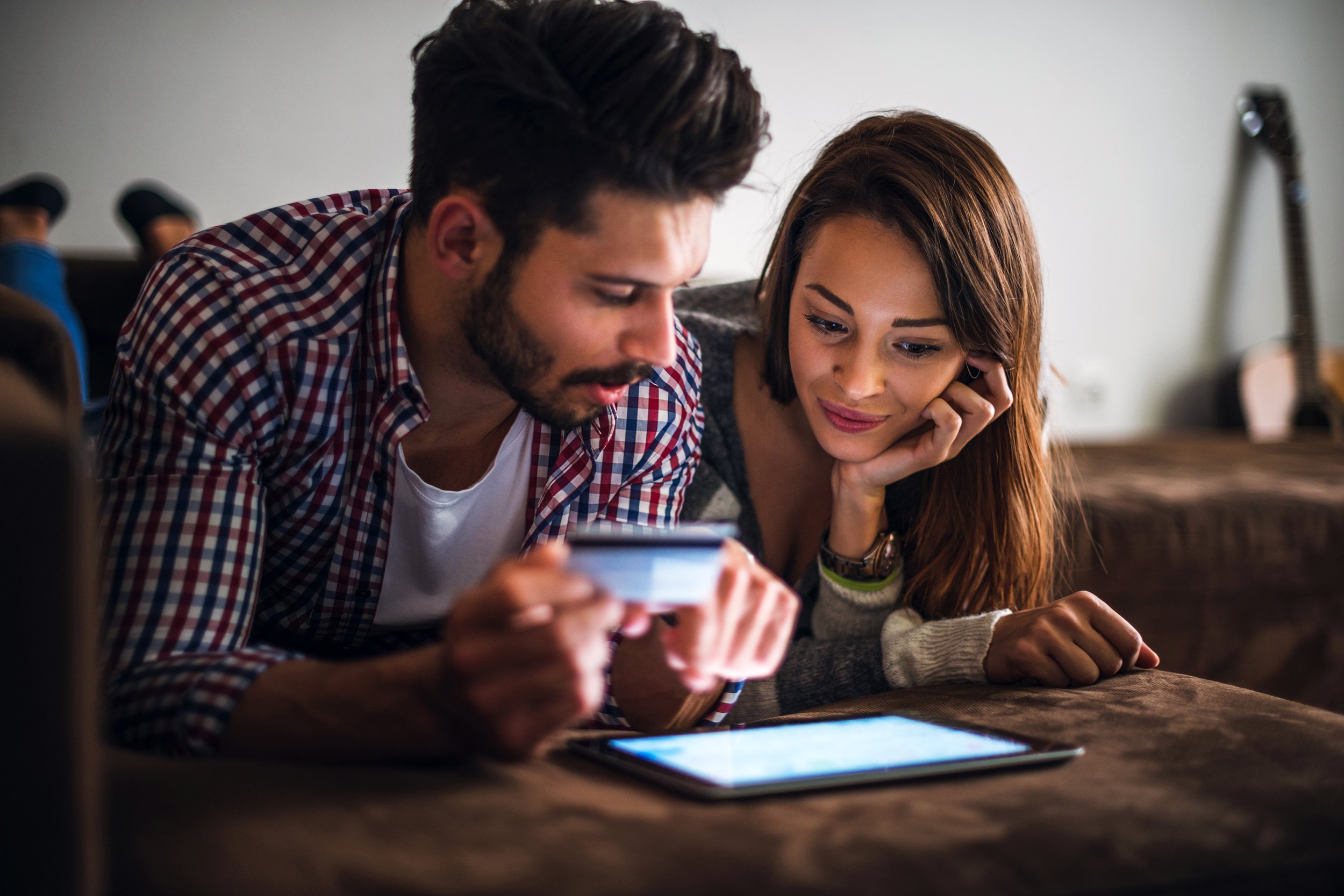 Couple looking at tablet on bed with credit card