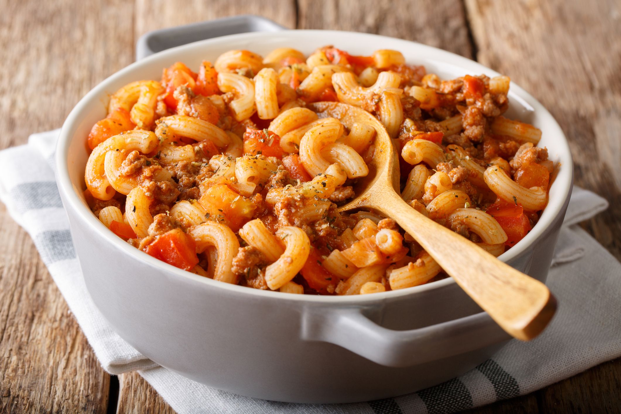 american chop suey, american goulash, with elbow pasta, beef and tomatoes close-up in a saucepan