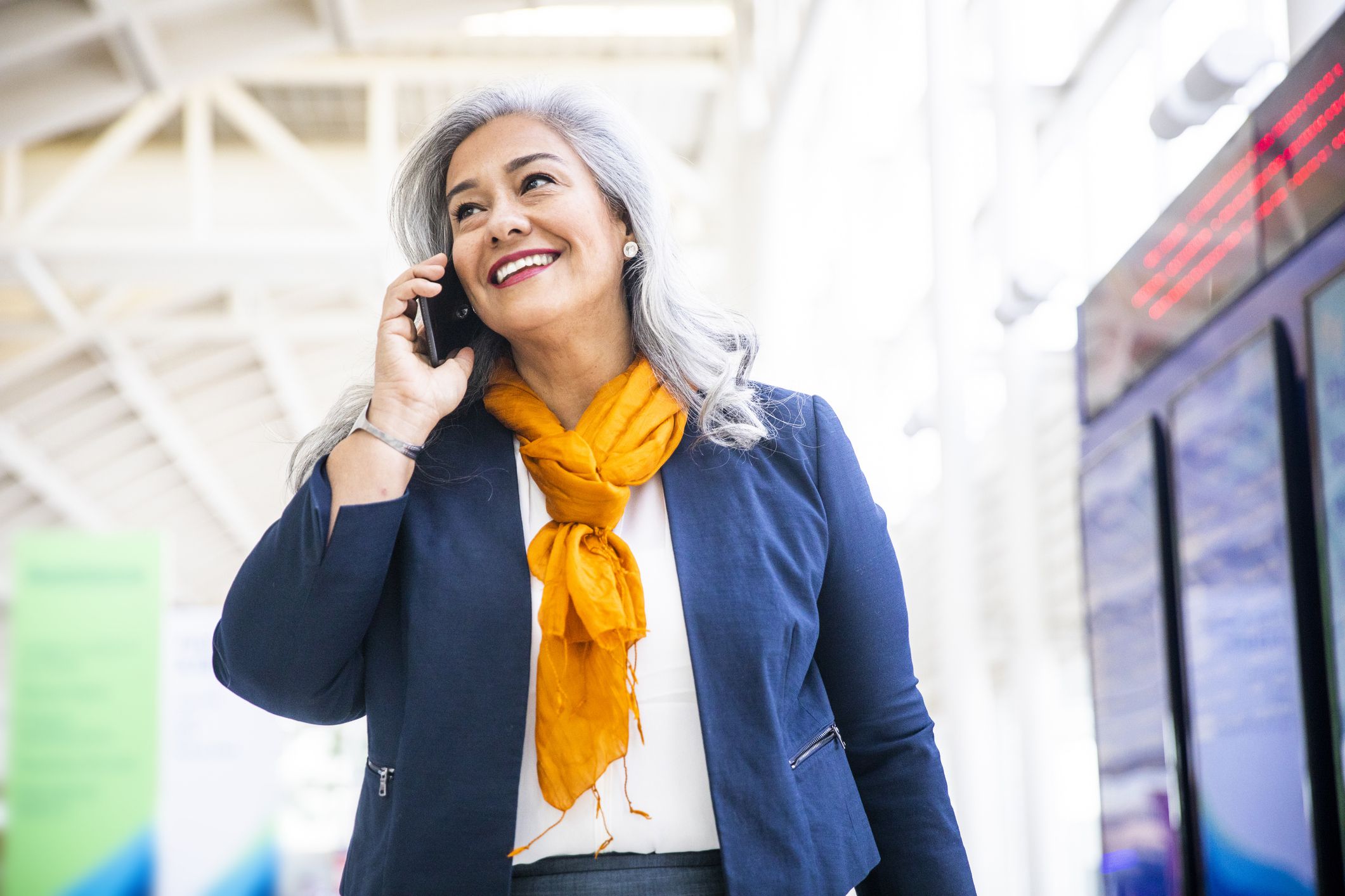 A Senior Hispanic Woman using her phone in the airport