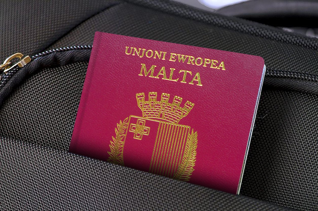 A Malta passport with gold text and emblem is partially visible in the front pocket of a black bag with a zipper.