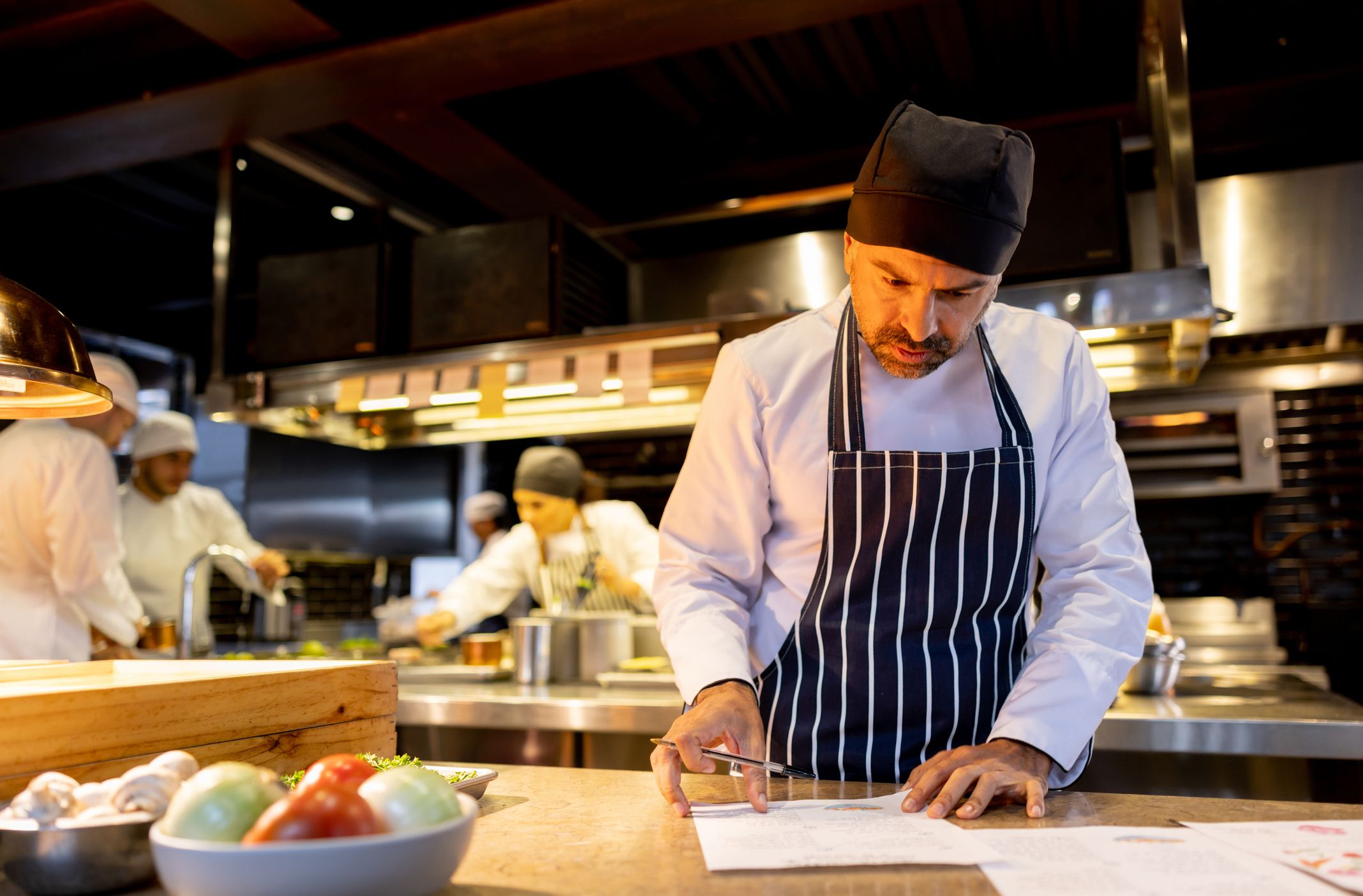 Latin American chef working at a restaurant and looking at the recipes for the menu - food and drink concepts
