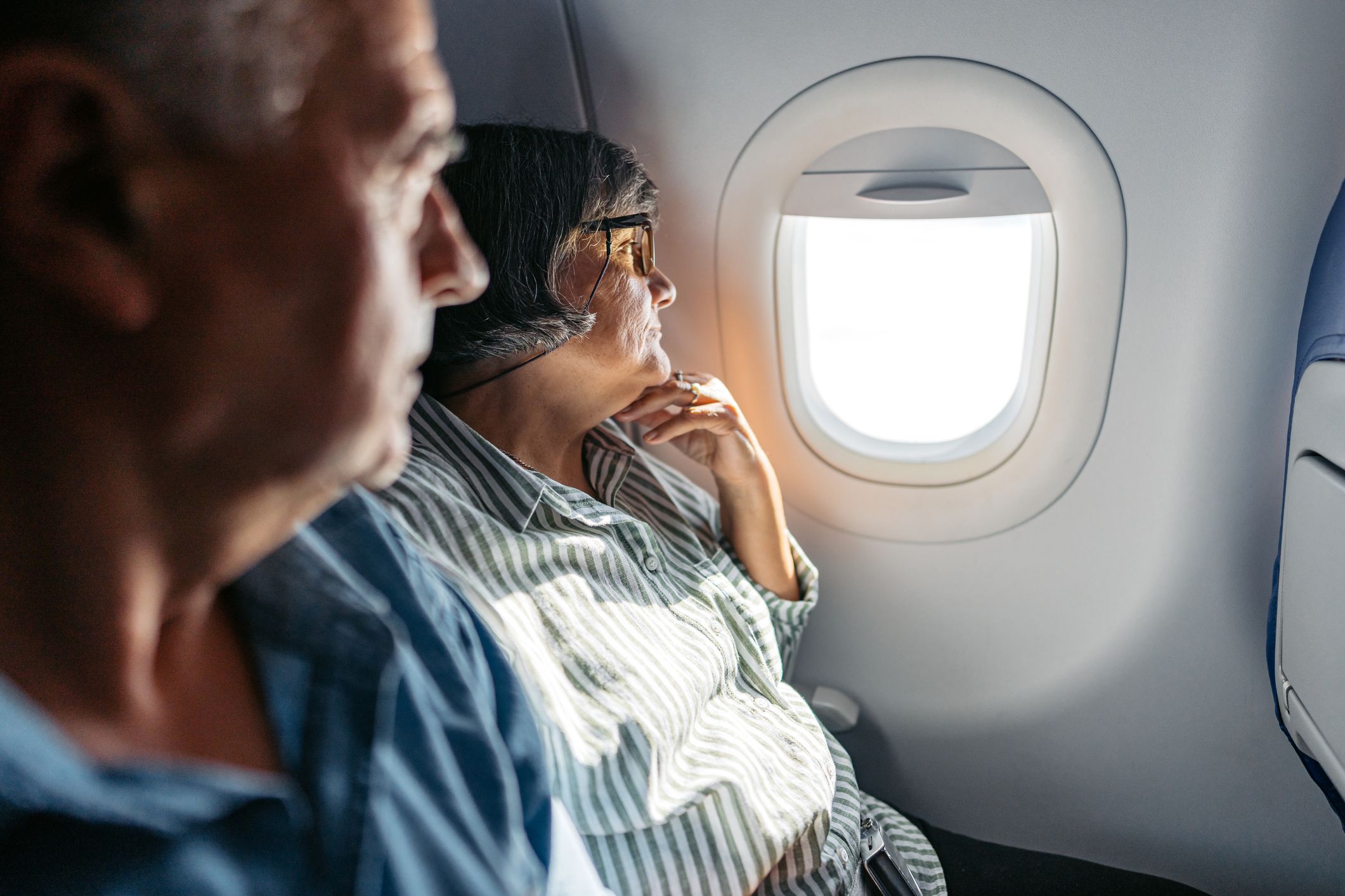 Senior couple looking out the window of an Airplane.