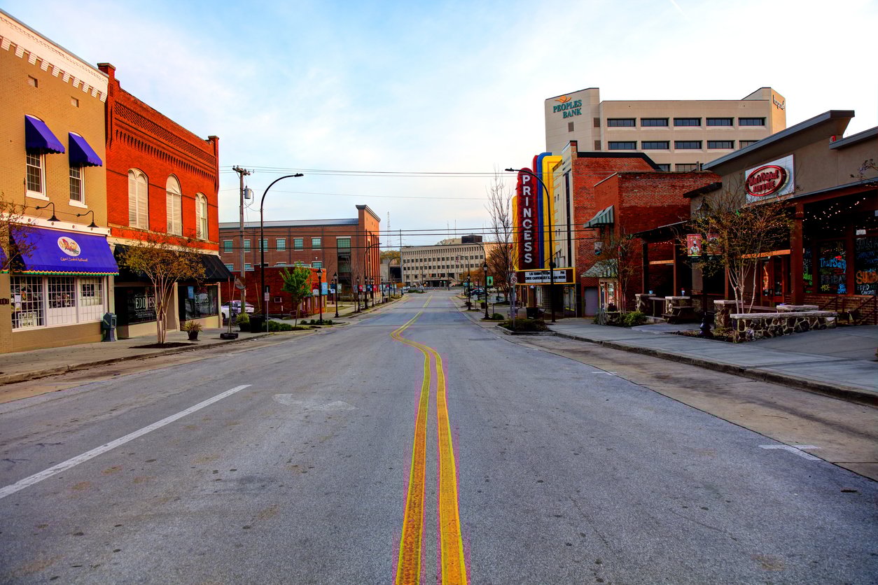 A quiet downtown street with historic brick buildings, a yellow double line, the "Princess" theater sign on the right, and a modern office building in the background under a clear sky.