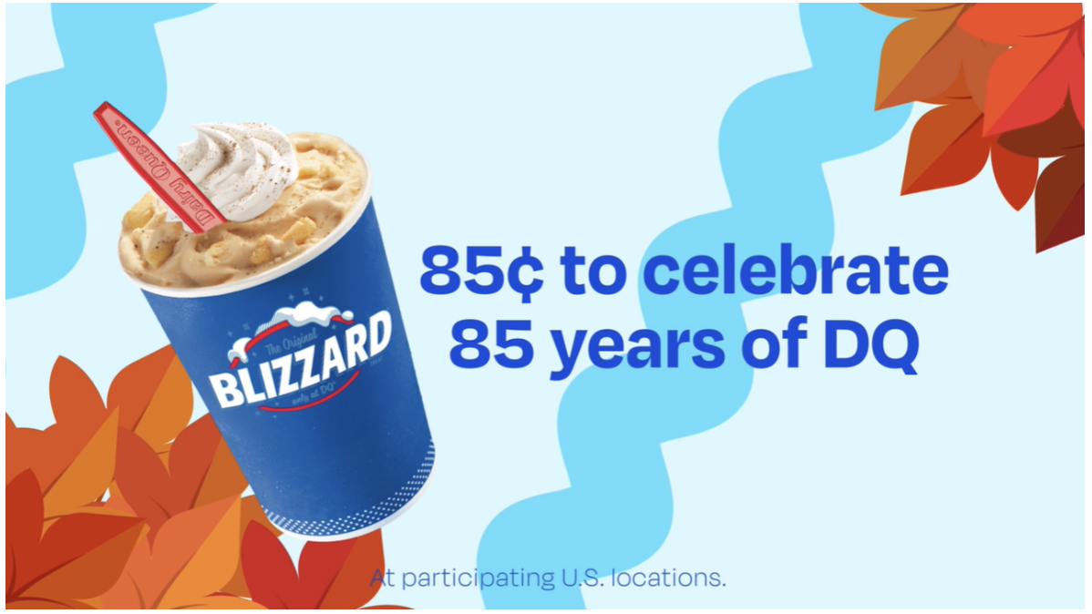 A Dairy Queen Blizzard in a blue cup with whipped cream and a red spoon is shown beside the text “85¢ to celebrate 85 years of DQ” on a light blue background with orange and red autumn leaves.