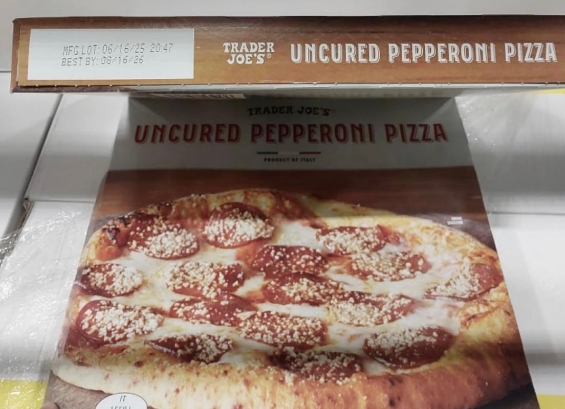 A Trader Joe's boxed uncured pepperoni pizza shows a photo of the pizza topped with pepperoni slices and melted cheese. The box displays the best-by date and product label.