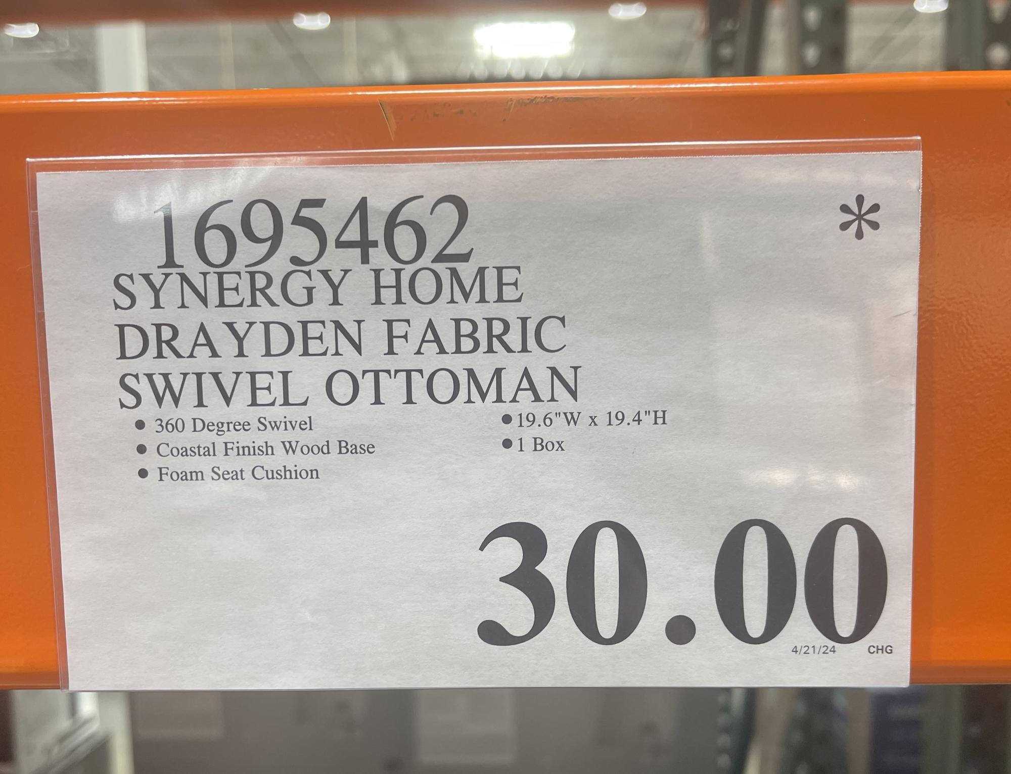 A Costco store shelf sign displays details for the Synergy Home Drayden Fabric Swivel Ottoman: 360-degree swivel, coastal finish wood base, foam seat cushion, size 19.6"W x 19.4"H, 1 box, price $30.00.