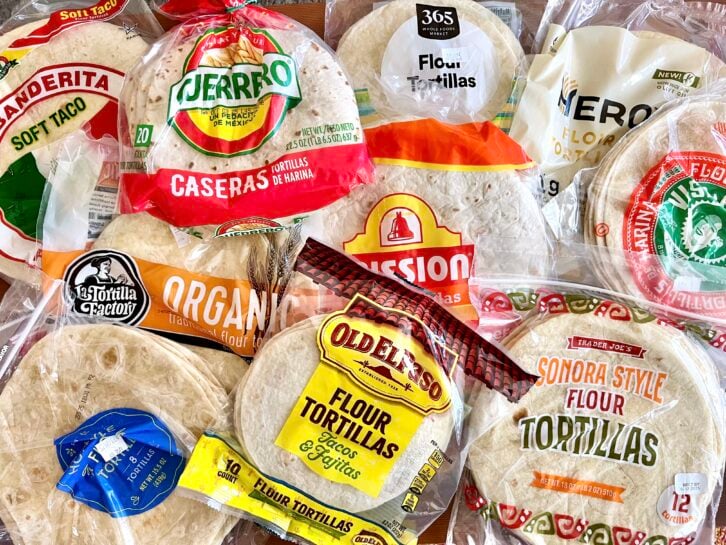 An assortment of packaged flour tortillas from various brands, including Mission, Old El Paso, Guerrero, Tortilla Factory, and others, overlapping each other on a flat surface.