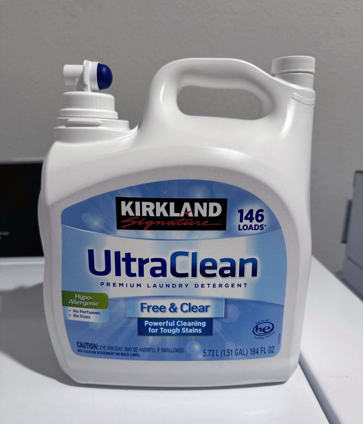 A white container of Kirkland Signature UltraClean Free & Clear premium laundry detergent sits on a surface. A favorite among Costco products loved by shoppers, its label advertises 146 loads, hypoallergenic, powerful cleaning, and 5.73 L (1.51 gal) size.