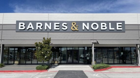 The exterior of a Barnes & Noble bookstore, featuring large glass windows, a prominent sign with the store’s name, and a small tree in front of the entrance.