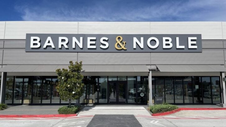 The exterior of a Barnes & Noble bookstore, featuring large glass windows, a prominent sign with the store’s name, and a small tree in front of the entrance.