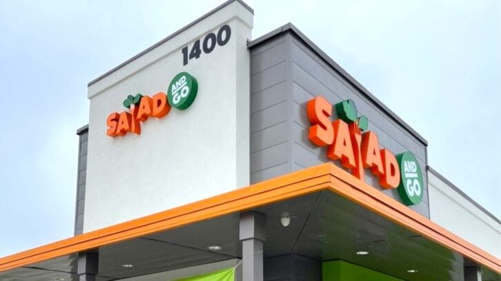 A modern building with gray walls and orange trim displays the "Salad and Go" logo in orange and green letters. The street number "1400" is visible at the top corner of the building.