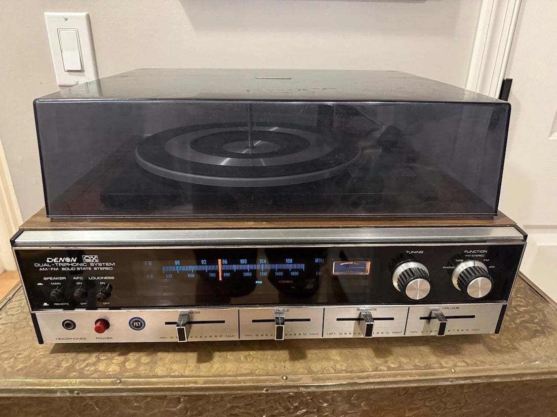 A vintage Diran dual stereo system with a turntable on top, dust cover closed, and a control panel featuring knobs, switches, and a radio frequency display on the front.