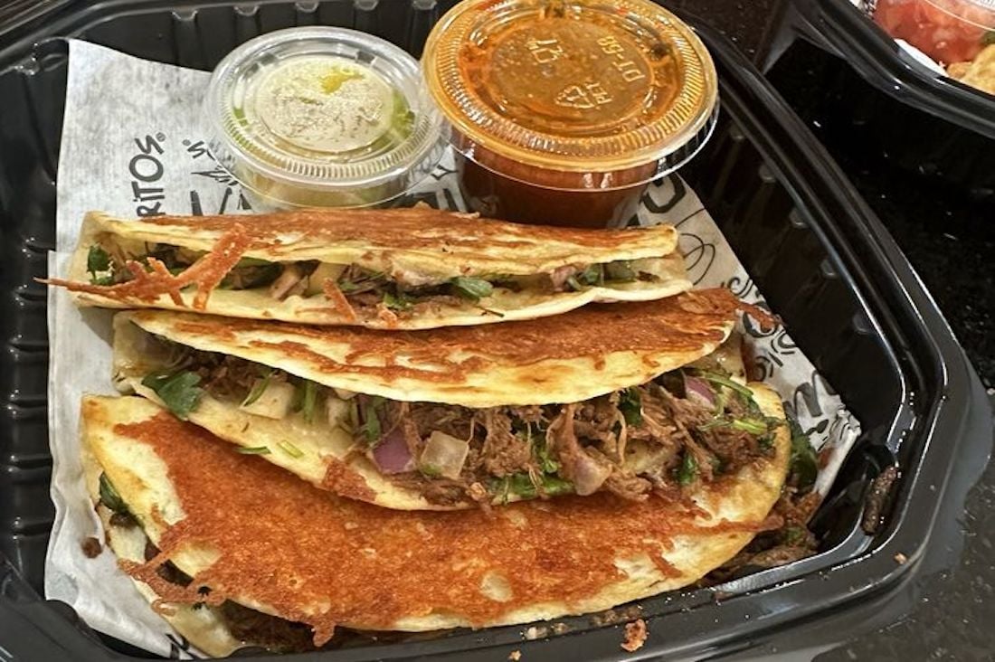 A stack of quesadillas with sauce in a black tray