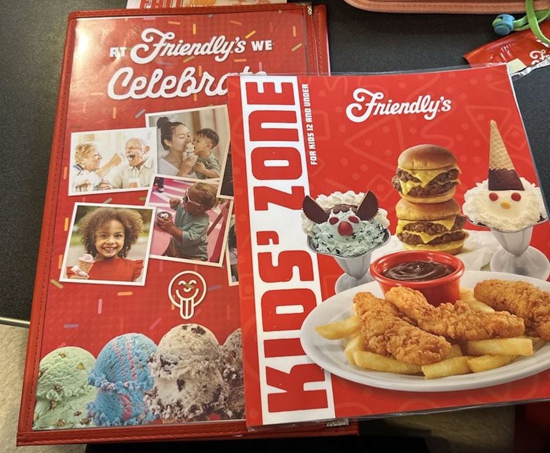 Two colorful menus from Friendly's restaurant are shown on a table. One menu says “Celebrate” with family photos, while the “Kids' Zone” menu displays burgers, fries, chicken tenders, and ice cream sundaes.