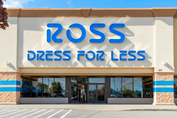 The front entrance of a Ross Dress for Less store, featuring large blue signage above the glass doors and windows, with a clear sky and parking lot in view.