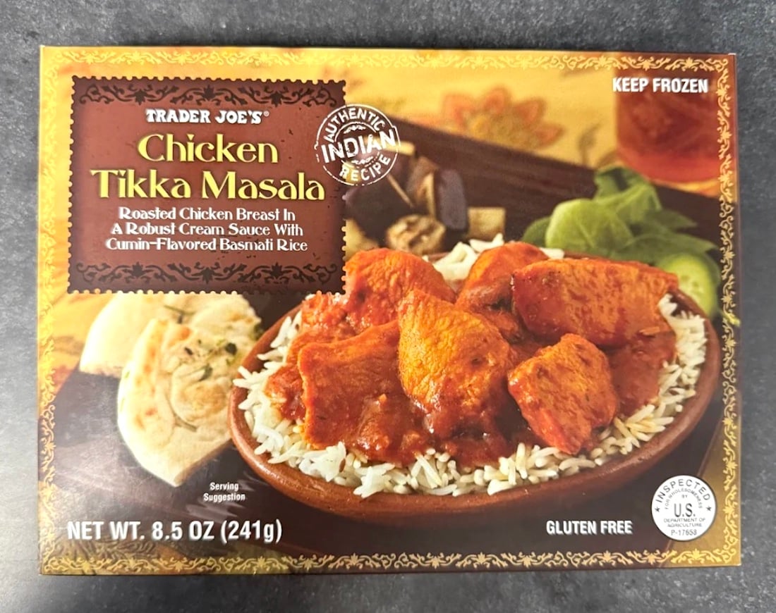 A Trader Joe's Chicken Tikka Masala frozen meal box, showing roasted chicken in orange sauce served over rice with naan bread on the side. The packaging highlights it as gluten free and an authentic Indian recipe.