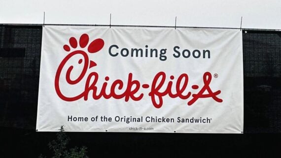 A white banner with "Coming Soon Chick-fil-A Home of the Original Chicken Sandwich" in red and black text, announcing a new Chick-fil-A restaurant opening soon.