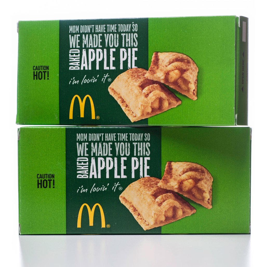 Two green McDonald's apple pie boxes are stacked, each featuring an image of a baked apple pie and the text "We made you this apple pie" with the McDonald's logo and the phrase "i'm lovin' it.