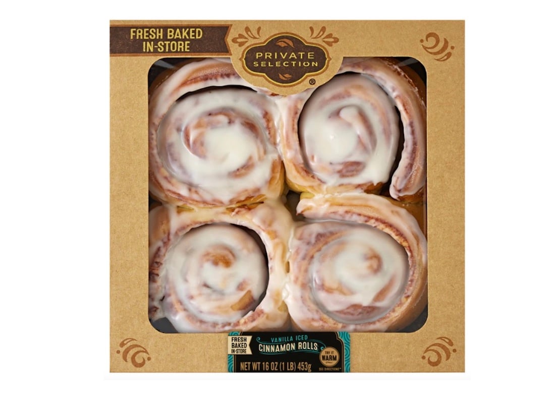 A box of four vanilla iced cinnamon rolls from Private Selection, visible through a clear window in a brown package labeled "Fresh Baked In-Store." The cinnamon rolls are topped with white icing.