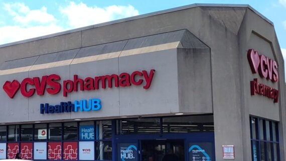 The entrance of a CVS Pharmacy store, featuring red "CVS pharmacy" and blue "HealthHUB" signs above the doors, with part of a cloudy sky visible in the background.