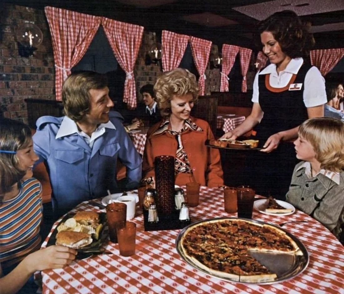 A group of people sitting at a table with pizzas