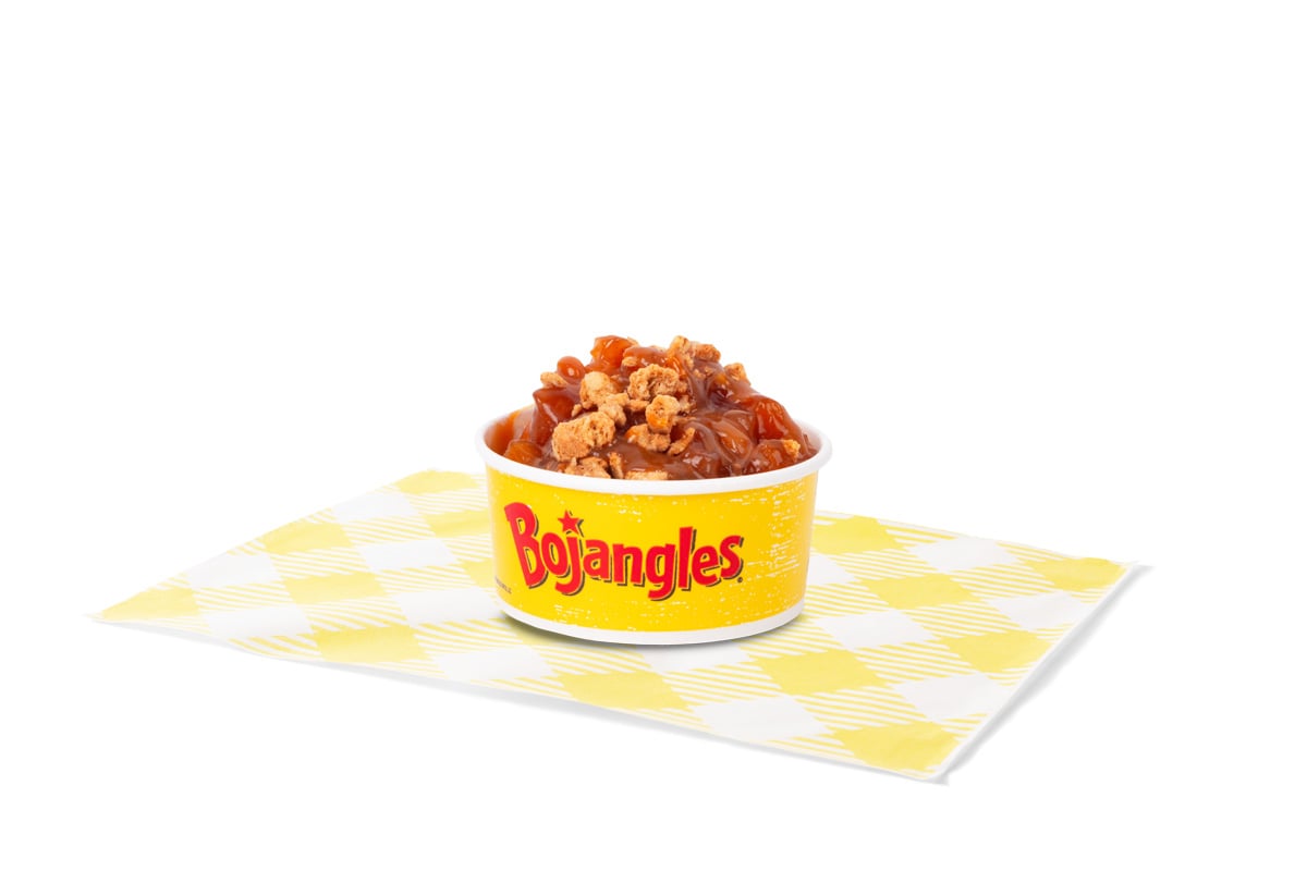 A yellow Bojangles cup from the new fast-food menu, filled with baked beans, sits on a white and yellow checkered napkin against a plain white background.