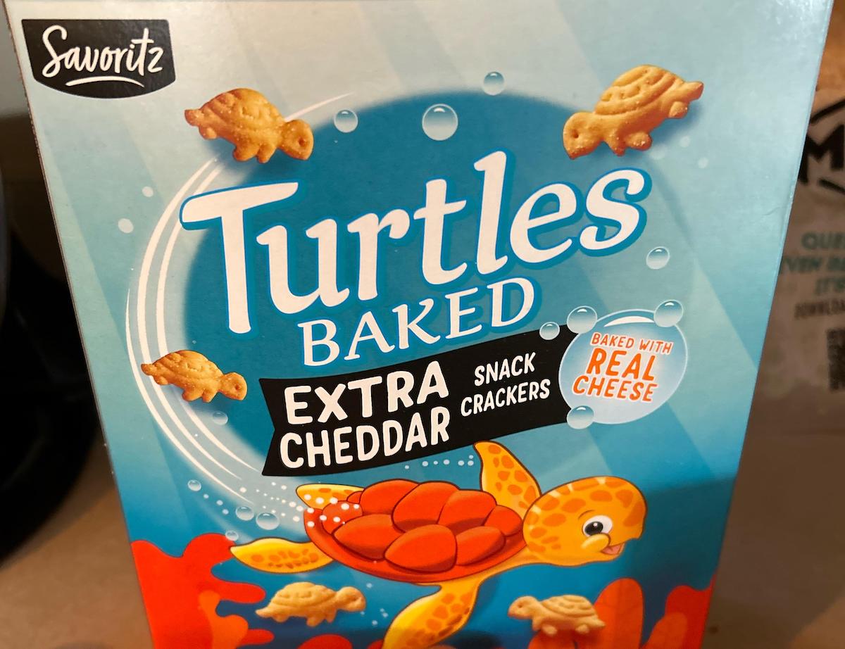Box of Savoritz Turtles Baked Extra Cheddar Snack Crackers, featuring cartoon turtle-shaped crackers and a smiling orange turtle swimming underwater on a blue and orange background.