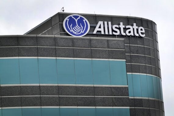 A modern gray office building with blue-tinted windows displays the Allstate logo and name at the top, reflecting its legacy among insurance CEOs. Two cupped hands in a circle stand out against the overcast sky.