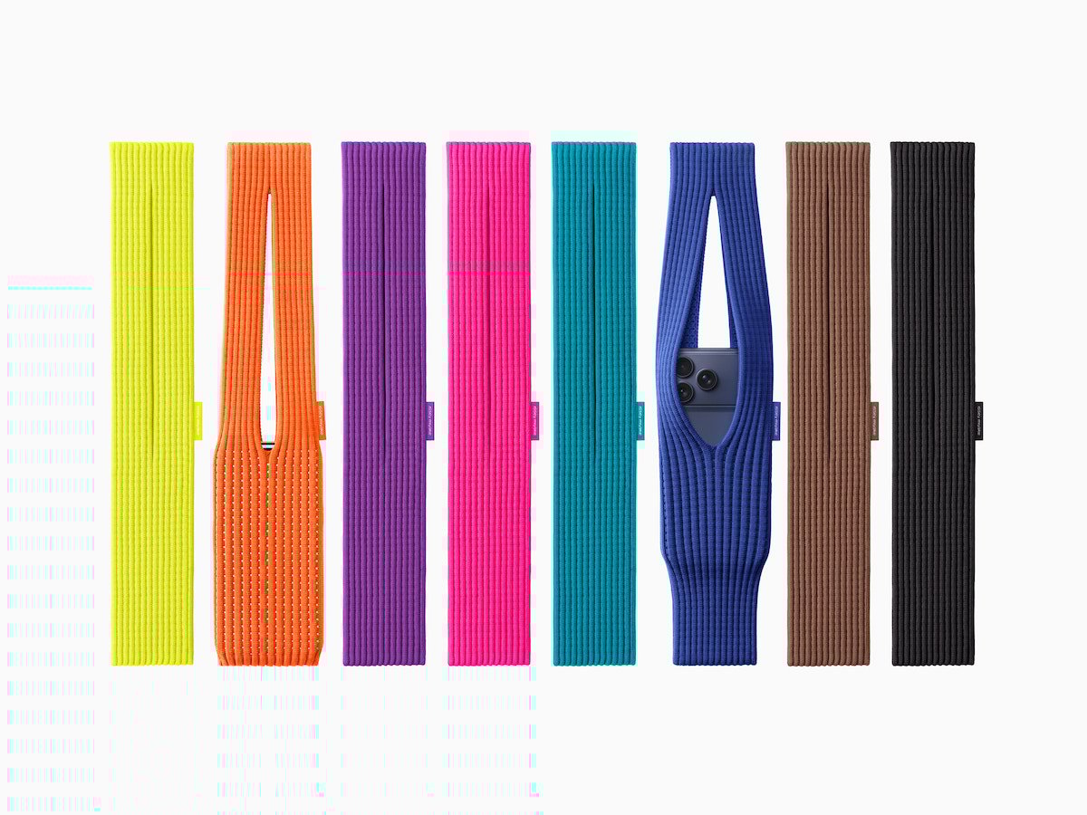 Eight colorful, ribbed fabric bands are lined up vertically. Each band is a different color, and two of them have central openings showing part of a smartphone inside. The background is plain white.