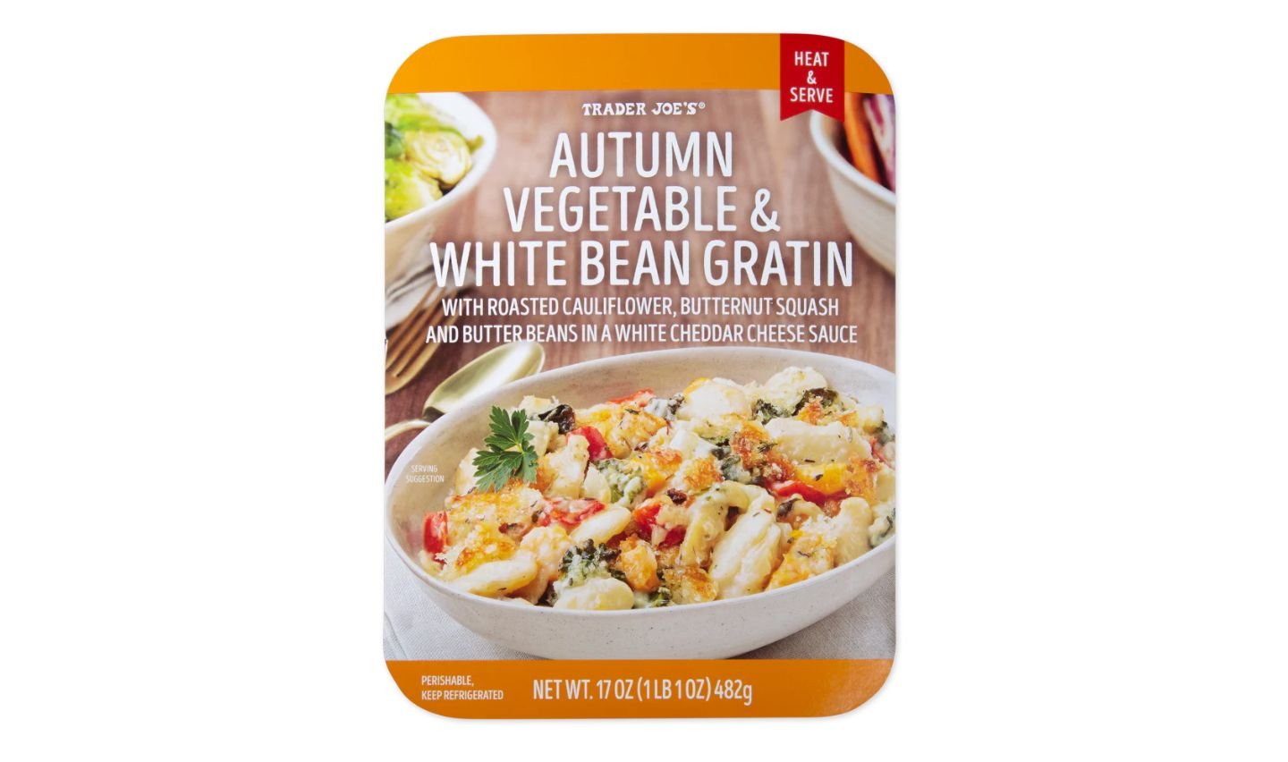 A Trader Joe’s package of Autumn Vegetable & White Bean Gratin, featuring an image of the dish with cauliflower, butternut squash, and beans in a creamy cheese sauce. The package is labeled “Heat & Serve.”
