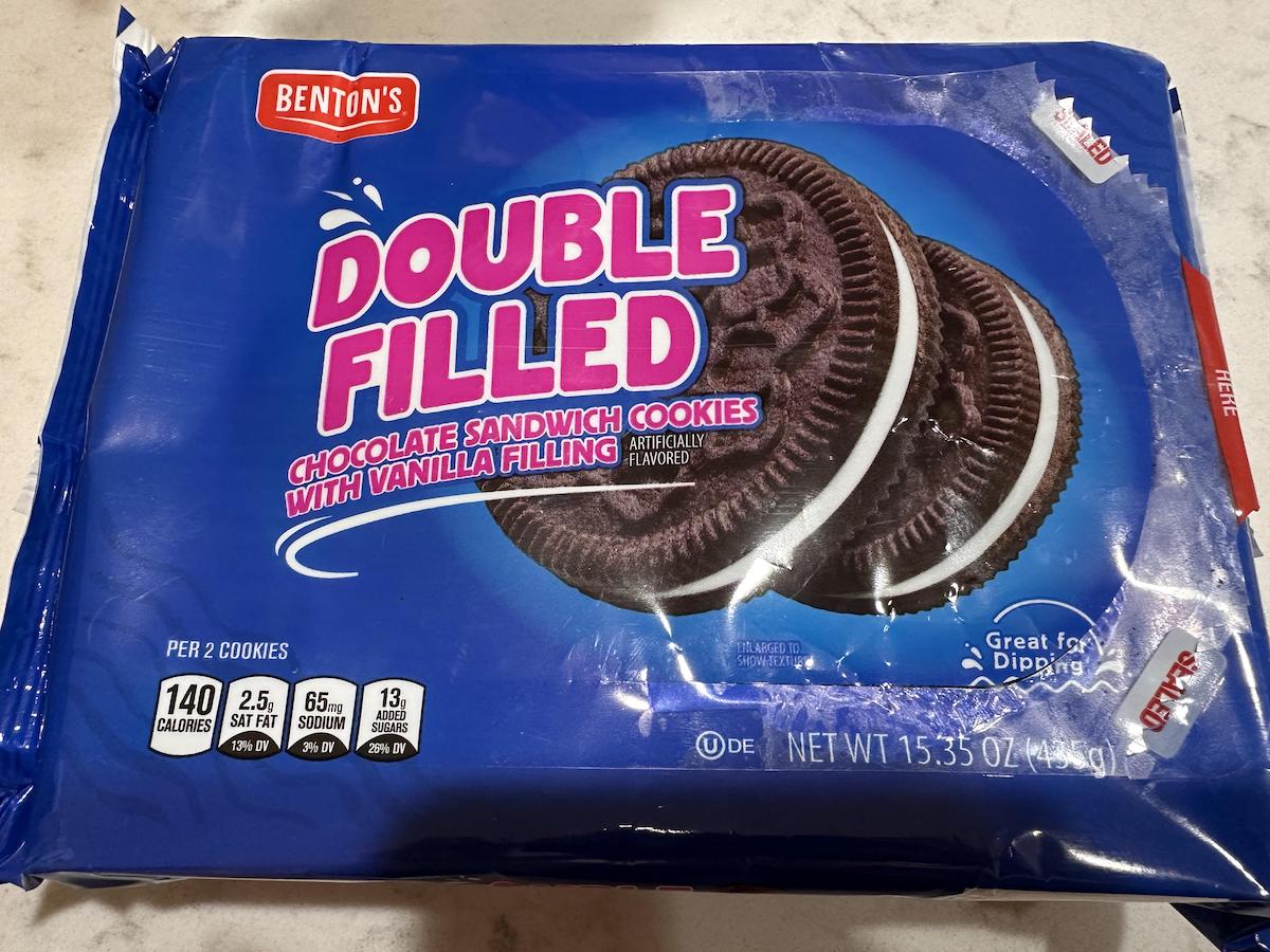 A blue package of Benton's Double Filled chocolate sandwich cookies with vanilla filling, featuring two cookies on the front. The package highlights nutritional info and the net weight of 15.35 oz.