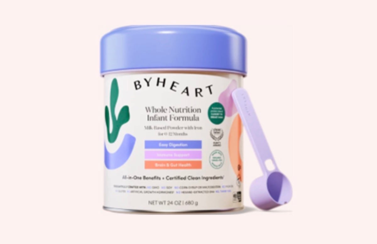 A container of ByHeart Whole Nutrition Infant Formula with a purple lid and matching scoop. The label highlights benefits like easy digestion, immune support, and brain & gut health. The container holds 24 oz (680 g) of formula.