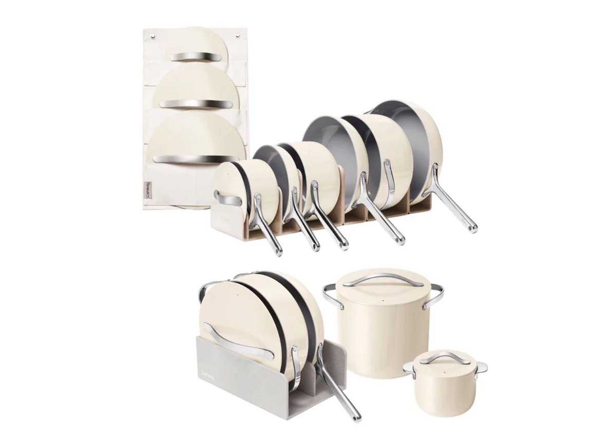 A set of cream-colored pots and pans with silver handles, neatly organized in racks. Some racks hold lids upright, and the cookware is arranged by size, including saucepans, frying pans, and stockpots.