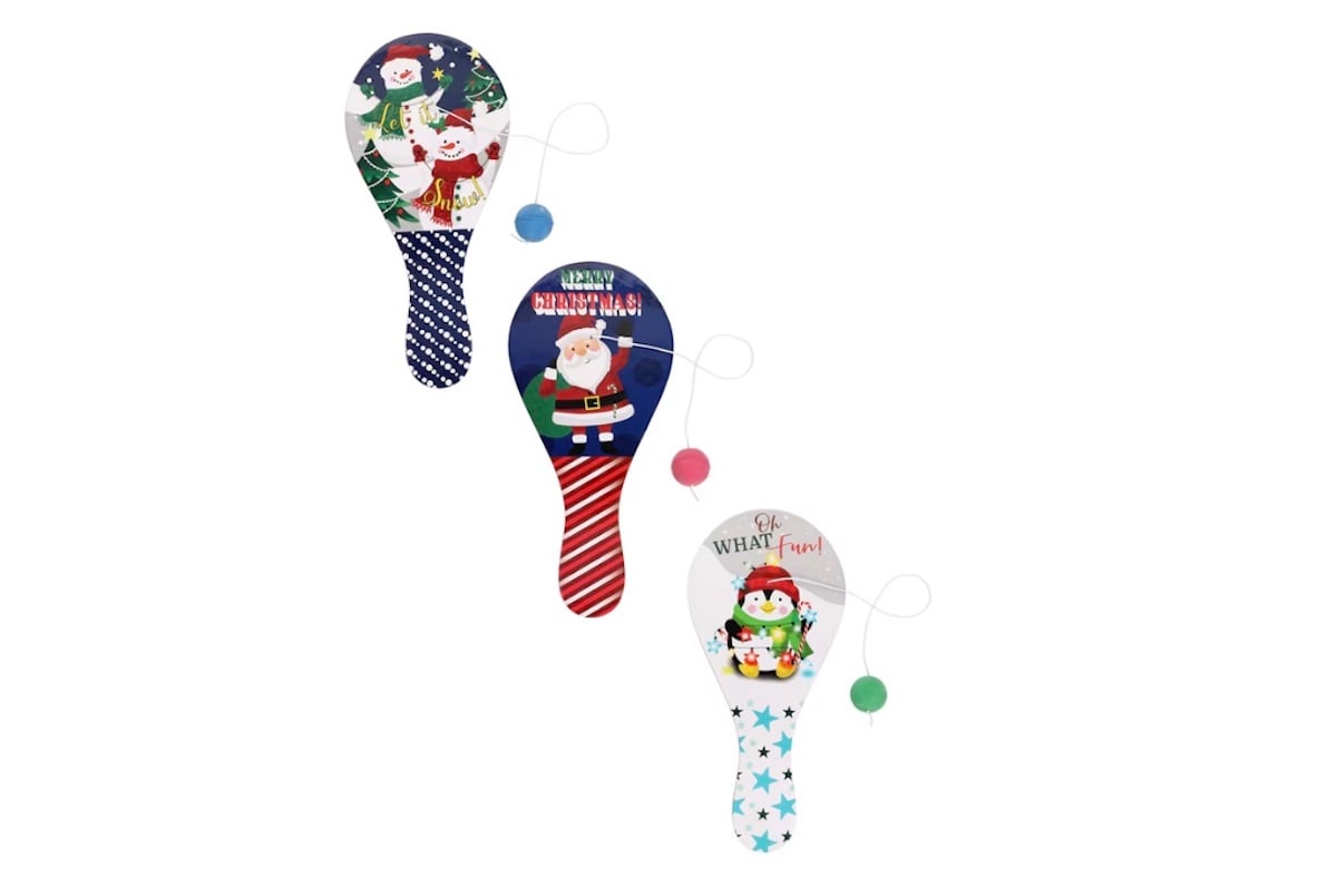 Three festive paddle ball toys with holiday designs featuring Santa Claus and a penguin, each with a ball attached by string. The paddles are decorated in red, green, blue, and white Christmas themes.