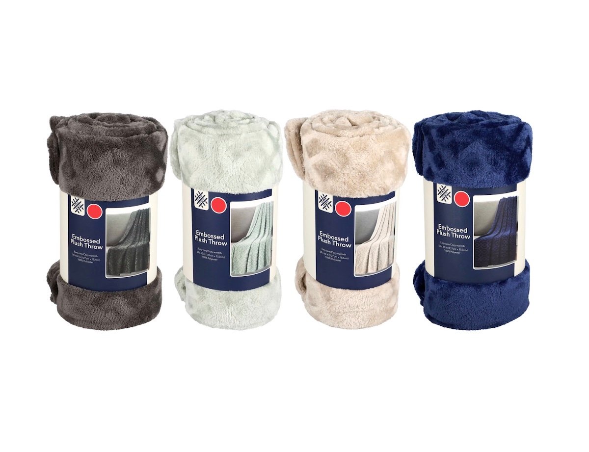 Four rolled-up embossed plush throws in dark gray, light mint, beige, and navy blue, each with a blue and white label showing the blanket texture and color.