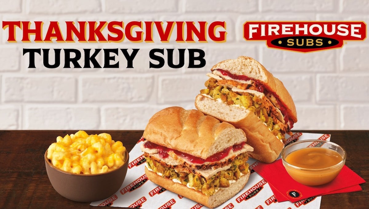 A Thanksgiving turkey sub sandwich filled with turkey, stuffing, and cranberry sauce is sliced and displayed with a bowl of macaroni and cheese and a dish of brown gravy. "THANKSGIVING TURKEY SUB" and "FIREHOUSE SUBS" logos appear above.