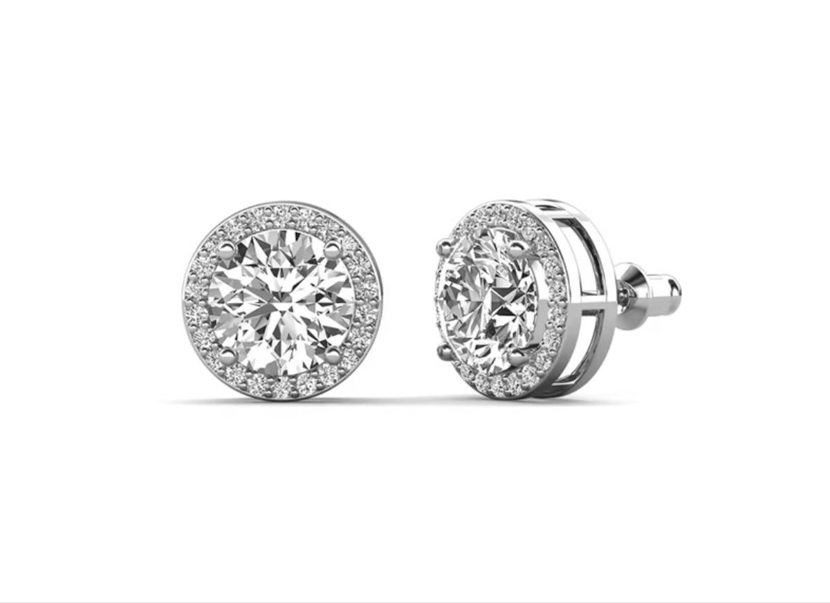 A pair of round diamond stud earrings with halo settings, featuring a large central diamond surrounded by smaller diamonds, set in white metal against a white background.